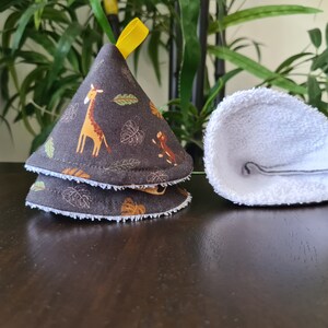 Könnte beinhalten: Zwei braune Stoff-Topflappen mit Dschungeltier-Druck, ein weißer Stoff-Topflappen, alle in Kegelform gefaltet.