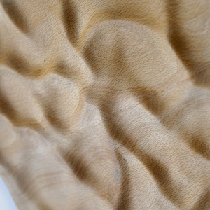 Puede incluir: Primer plano de una superficie de madera texturizada de color marr&oacute;n claro con un patr&oacute;n ondulado. La veta de la madera es visible y la superficie tiene un aspecto suave y t&aacute;ctil. El efecto general es natural y org&aacute;nico.