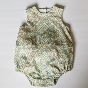 Può includere: Un body per neonato senza maniche con sfondo bianco e un motivo paisley in tonalità di verde, marrone e crema.