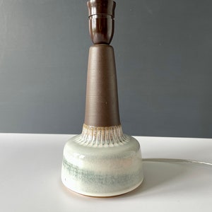 May include: A ceramic table lamp with a brown base and a white and green glazed shade.