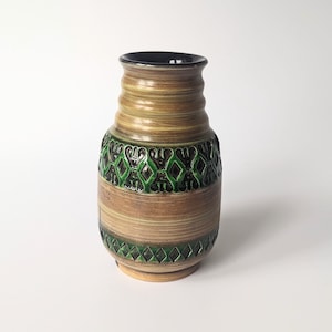 May include: A brown ceramic vase with green and black geometric designs. The vase has a rounded body and a narrow neck.