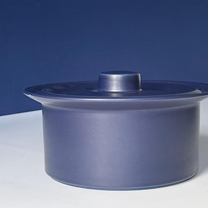 Könnte beinhalten: Eine dunkelblaue, abgedeckte Keramikschale mit einem abgerundeten Deckel. Die Schale ist aus einem glatten, glänzenden Material gefertigt.