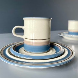 Könnte beinhalten: Ein Set aus blauen und weißen gestreiften Kaffeetassen und Untertassen. Die Tassen haben einen goldenen Rand und einen hellbraunen Streifen.