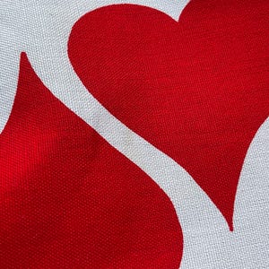 May include: Red fabric with a white heart design. The heart is outlined in white and has a white background.