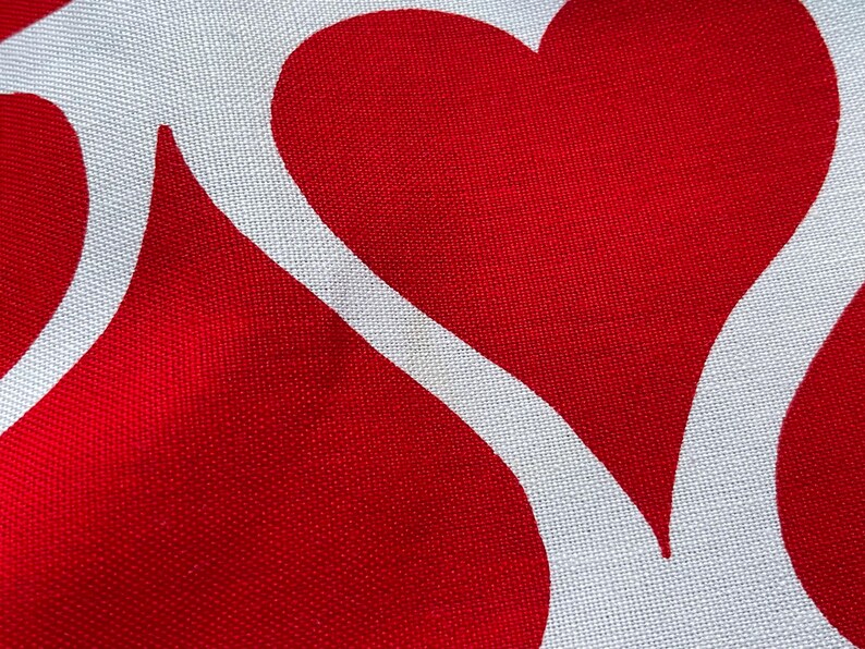 May include: Red fabric with a white heart design. The heart is outlined in white and has a white background.