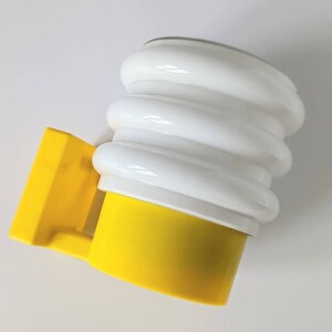 May include: A yellow and white wall sconce with a rounded, ribbed white shade and a yellow base. The sconce has a rectangular yellow mounting bracket.