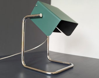 May include: A green metal desk lamp with a chrome base and a flexible arm. The lamp is on a gray surface.