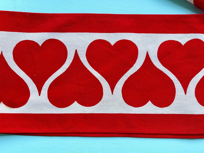 May include: Red and white fabric with a repeating pattern of white hearts on a red background.