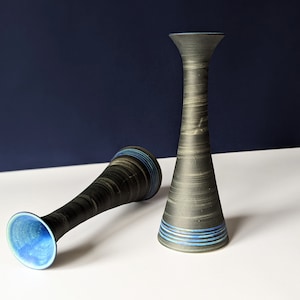 May include: Two black ceramic vases with blue and green stripes. The vases are tall and slender, with a flared opening.