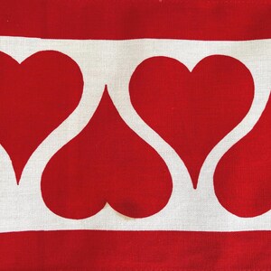 May include: A white fabric with a red heart pattern. The hearts are arranged in a row, with the points of the hearts facing each other.