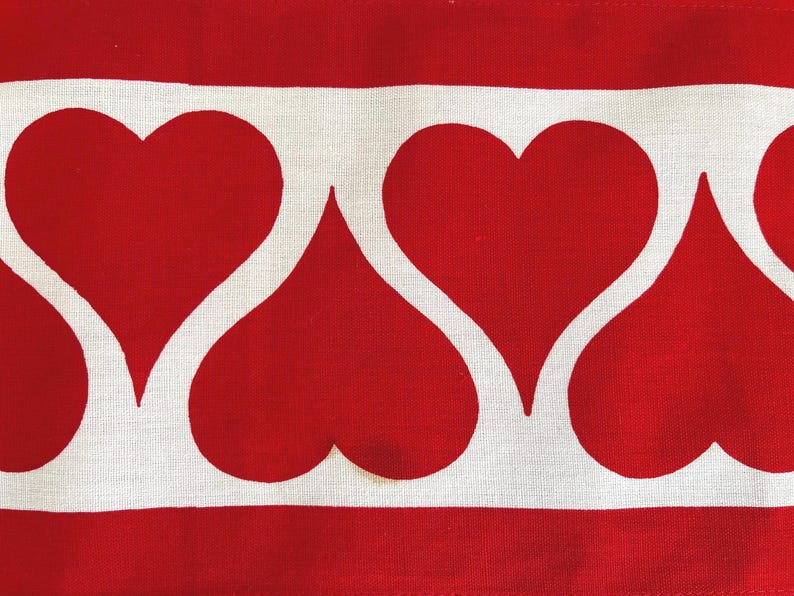 May include: A white fabric with a red heart pattern. The hearts are arranged in a row, with the points of the hearts facing each other.