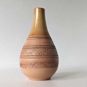 Può includere: Un vaso in ceramica marrone chiaro a forma di lacrima con intricati disegni marroni intorno al centro.