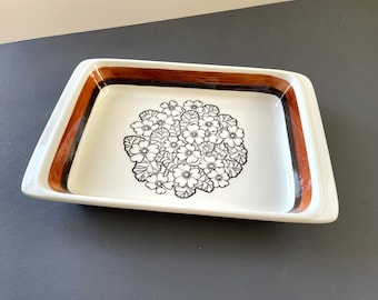 以下が含まれることがあります： 茶色と黒の花柄が描かれた白いセラミック製のベーキングディッシュ。長方形で角が丸みを帯びています。