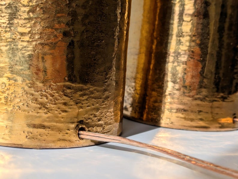 May include: Two gold-toned table lamps with a textured finish and a cord connecting them.
