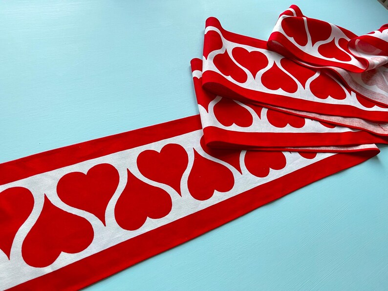 May include: Red and white fabric trim with a repeating pattern of white hearts on a red background.