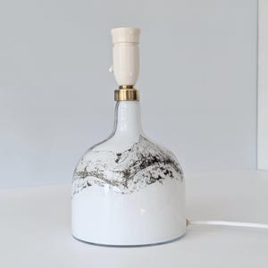 May include: White ceramic table lamp with a black and white abstract design on the base. The lamp has a white ceramic shade and a brass base.