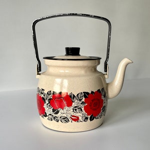 May include: A white enamel teapot with a black handle and a floral design featuring red roses and black leaves.