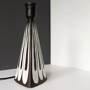 May include: A black and white ceramic table lamp with a geometric design. The lamp has a black cord and a black lampshade.