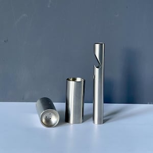 Può includere: Tre utensili da bar in acciaio inossidabile sono esposti su uno sfondo grigio. Gli utensili includono un saliera, un bicchierino e un apribottiglie. Gli articoli sono cilindrici e hanno una finitura in metallo spazzolato.