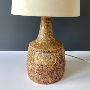 May include: A ceramic table lamp with a brown and white textured base and a white fabric lampshade.