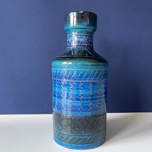 Op de afbeelding: Een blauwe en zwarte keramische vaas met een geometrisch patroon. De vaas heeft een brede opening en een smalle hals.