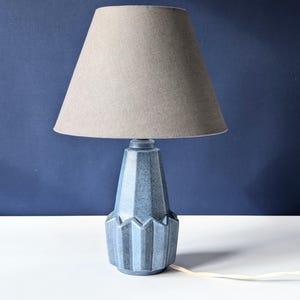 May include: A blue ceramic table lamp with a gray fabric lampshade. The lamp base has a geometric design.