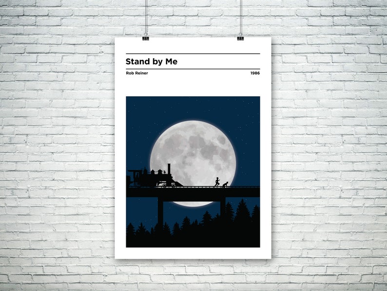 May include: A black and white minimalist poster with the title "Stand by Me" and the director's name "Rob Reiner" and the year "1986". The poster features a silhouette of a train crossing a bridge under a large full moon.