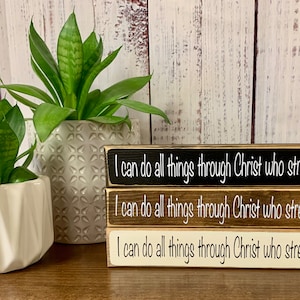 May include: Three wooden signs stacked on top of each other. Each sign has the same text in white lettering on a black background: "I can do all things through Christ who strengthens me."