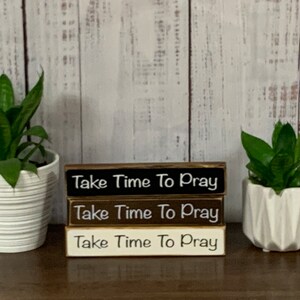 May include: Three wooden signs stacked on top of each other. Each sign has the words "Take Time To Pray" written in white on a black, brown, and white background.