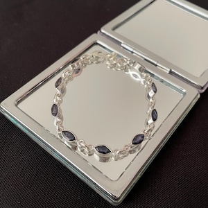 Può includere: Un braccialetto d'argento con un design a catena e pietre ovali di colore viola scuro.