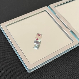 Può includere: Un anello d'argento con tre pietre rosse a forma di cuore incastonate nella fascia.