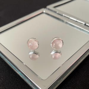 Op de afbeelding: Een paar zilveren oorbelletjes met roze rozenkwarts stenen.