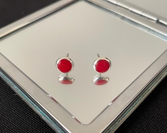May include: A pair of silver stud earrings with small, round, red gemstones.