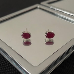 Può includere: Un paio di orecchini a lobo in argento con pietre preziose rosse di forma ovale.