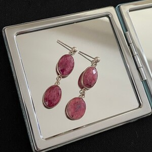 Op de afbeelding: Een paar oorhangers met twee ovale roze edelstenen aan elke oorhanger.
