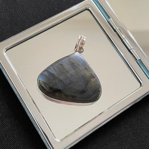 Peut inclure: Un pendentif en argent avec une pierre précieuse en labradorite bleu foncé. Le pendentif est présenté sur un miroir argenté.