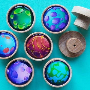 May include: Seven wooden knobs with colourful planets painted on them. The planets are different colours and have different patterns. The knobs are all the same size and shape.