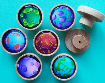 May include: Seven wooden knobs with colourful planets painted on them. The planets are different colours and have different patterns. The knobs are all the same size and shape.
