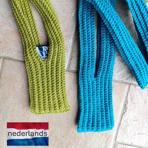 Op de afbeelding: Twee gebreide, open, groene en blauwgroene, lange, rechthoekige haakzakken. De groene tas heeft een klein vakje met een patroonstof aan de binnenkant. De tassen liggen op een lichtbruin betegeld oppervlak.