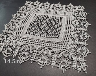 May include: A delicate, white crocheted doily with a square center and intricate floral designs around the edges. The doily measures 14.5 inches in diameter.