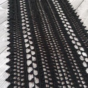 Peut inclure: Écharpe en crochet noire avec un motif de dentelle délicat. L'écharpe est réalisée avec un fil fin et a une texture douce et fluide.