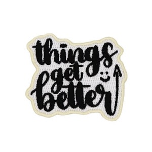 Könnte beinhalten: Schwarzer gestickter Aufnäher mit weißen Nähten. Der Aufnäher zeigt den Text "things get better" mit einem nach oben zeigenden Pfeil und einem Smiley.
