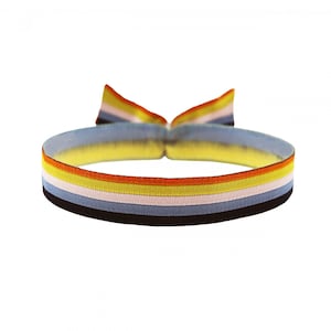 Könnte beinhalten: Ein mehrfarbiger Gummiband für Haare mit Streifen in Schwarz, Blau, Hellrosa, Gelb und Orange.