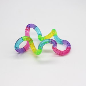 Pode incluir: Um brinquedo fidget colorido e flexível com um design ondulado e interligado. Os segmentos são translúcidos e vêm em uma variedade de cores brilhantes, incluindo rosa, roxo, azul, verde e amarelo. O brinquedo foi projetado para ser manipulado e torcido.