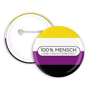 Può includere: Due spille rotonde. Una spilla è bianca con un design giallo, bianco, viola e nero. L'altra spilla è bianca con uno spillo argentato. La spilla ha il testo "100% MENSCH LIEBE RECHT RESPEKT".