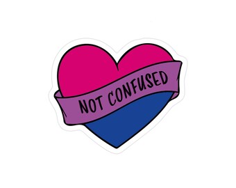 May include: A heart-shaped sticker with a pink and blue design, bisexuality pride colors. A purple banner across the heart reads "NOT CONFUSED" in black text. The sticker is on a white background.