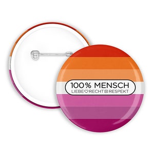 Può includere: Un bottone rotondo con un design arcobaleno e il testo "100% MENSCH LIEBE ♥ RECHT ✊ RESPEKT".