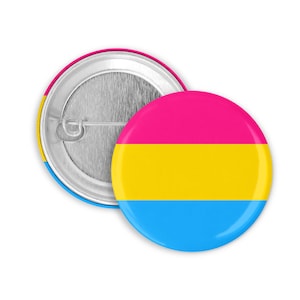 Könnte beinhalten: Ein runder Ansteckbutton mit einem Design aus horizontalen rosa, gelben und blauen Streifen. Der Button hat eine glänzende Oberfläche und eine silberne Metallrückseite mit Sicherheitsnadel. Er repräsentiert die Pansexuelle Pride-Flagge.