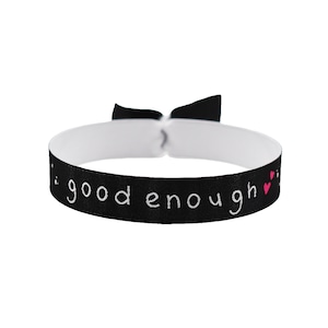 May include: Black elastic bracelet with white text that reads "...good enough..." and two pink hearts.