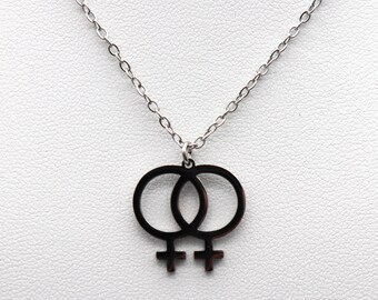 May include: A silver chain necklace with a pendant featuring two interlocking female symbols.